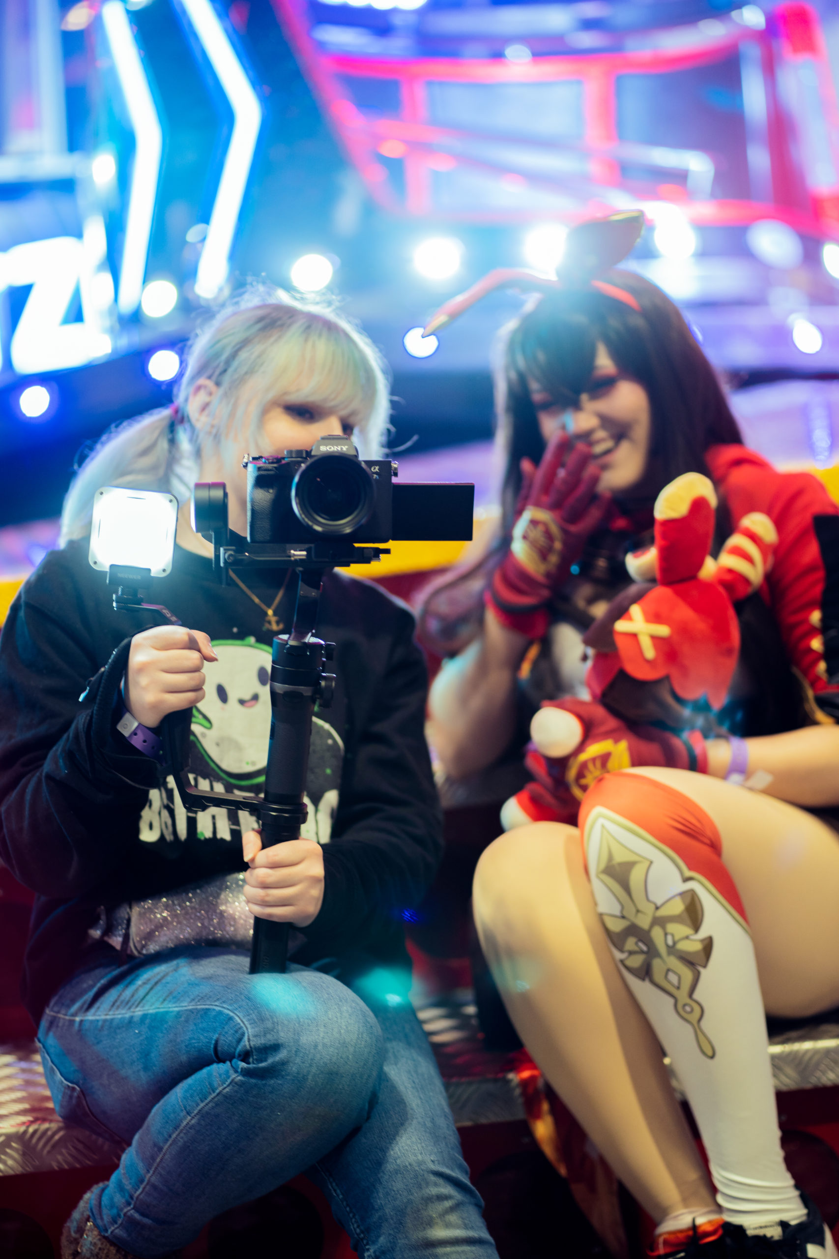 Two people sit on the edge of a carousel reacting to a video that was just filmed via the camera on a gimbal.