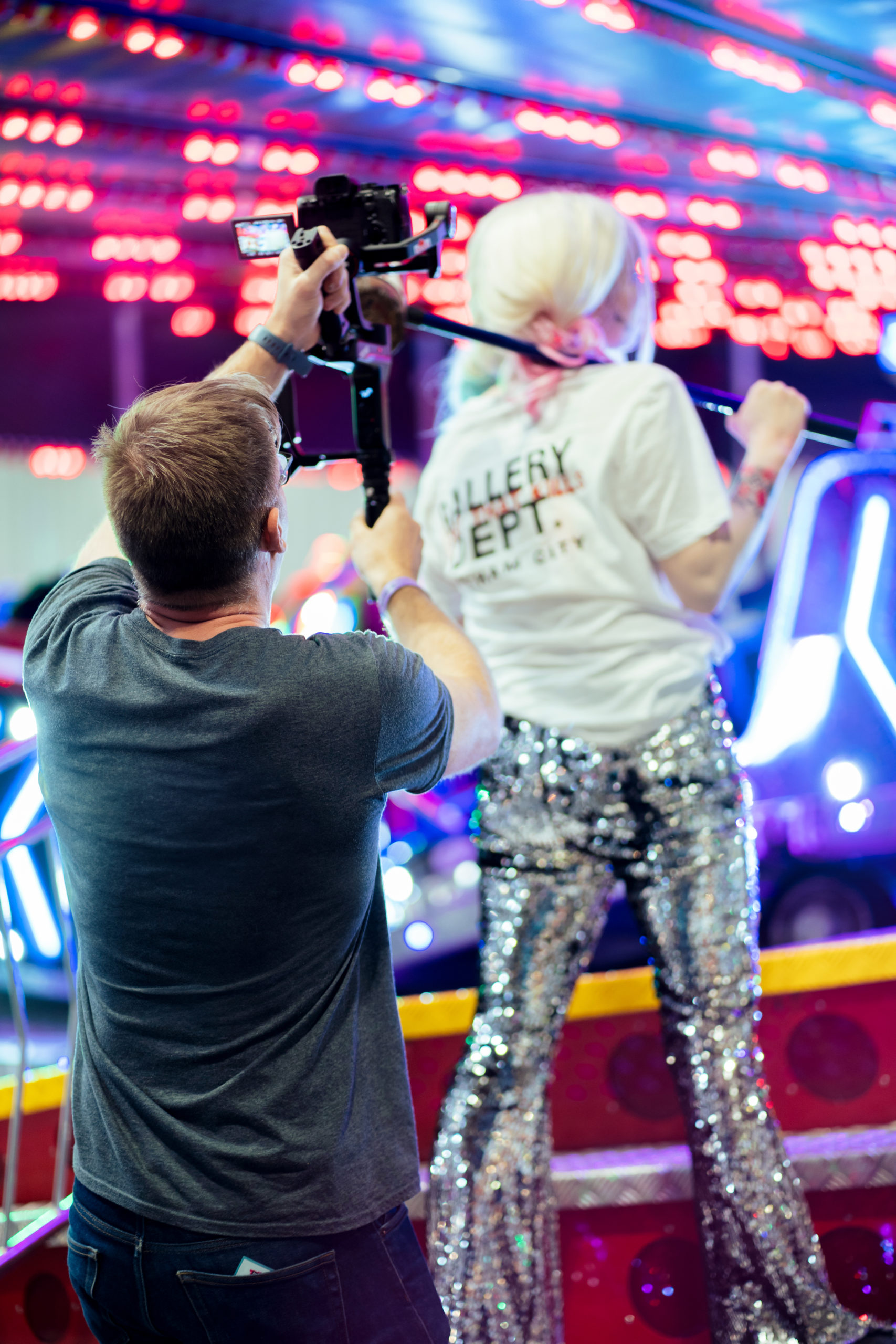 Man films the back of a Harley Quinn cosplayer on the edge of a carousel with a gimbal